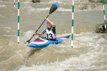 Naklejka premium White water kayak athlete racing through a downstream slalom gate
