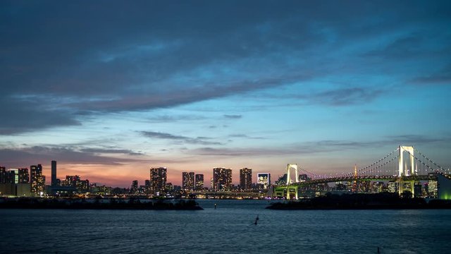 Amazing timelapse of Tokyo skyline with Rainbow Bridge and Tokyo bay at evening after sunset