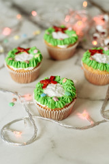 New Year's sweets on a marble table. Christmas cupcakes decorated with mastic and cream