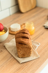 New bread on napkin on the kitchen table, cheese and fruit, healthy breakfast