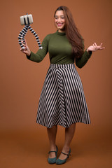 Young beautiful Indian woman vlogging with mobile phone against