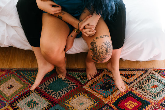two young women sitting on the bed give each other hands in colorful room