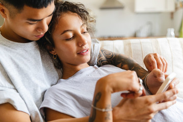 Beautiful couple on the sofa using mobile phone together