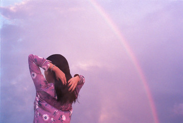 Woman admiring sunset with rainbow