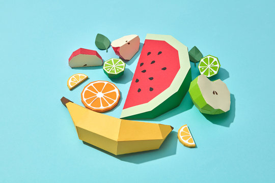 Handcraft paper fresh banana, slices of watermelon, orange, lime, lemon and mint leaves on a blue background with space for text. A set of different fruits for a healthy salad. Flat lay