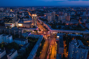 Aerial view of night city with illuminated roads, car traffic and different buildings, drone shot