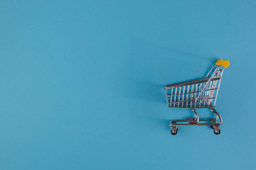 Shopaholic. Buyer. Shopping concept. Close-up. Isolated shopping trolley on a blue background. Copy...
