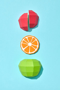 Handcraft paper half green apple, piece of orange and red apple on a blue background with copy space. Healthy fruit. Flat lay