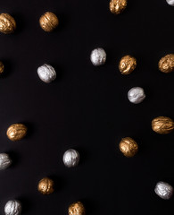 Painted golden and silver walnuts on black background