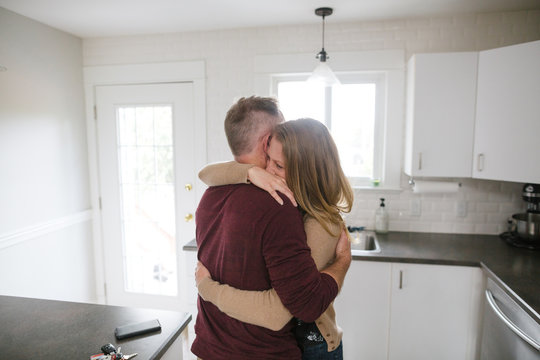 Serious couple hugging together at home.