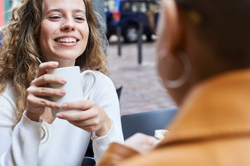 Blonde young woman having coffee with friend.