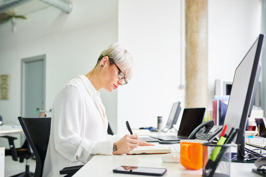 Stylish woman with notepad at desk