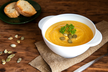 Pumpkin cream soup with croutons on a brown background