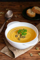 Pumpkin cream soup with croutons on a brown background
