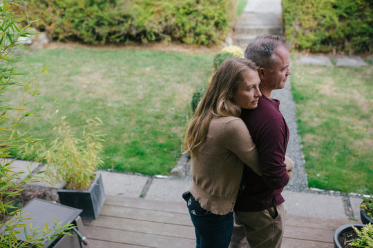 Serious couple hugging together at home.