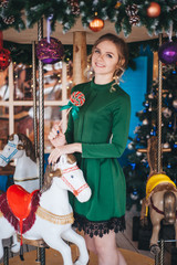 Fototapeta na wymiar Beautiful young woman rejoices near a carousel with horses. Christmas.