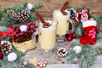 Two glasses with eggnog on the festive table with Christmas decor. Close-up.