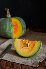 Green pumpkin with a slice on a wooden table