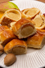 Fresh baked Dutch filled spicy cookies from puff pastry with almonds in autumn colors on dark wooden background