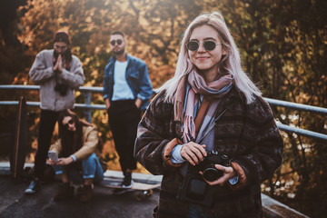 Fototapeta na wymiar Young positive woman in sunglasses has a nice walk in bright autumn day.