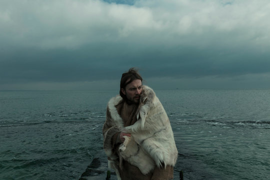 viking in the skin of an animal on the background of the gloomy sea