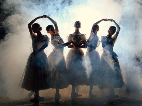 Ballerinas in dresses posing in darkness