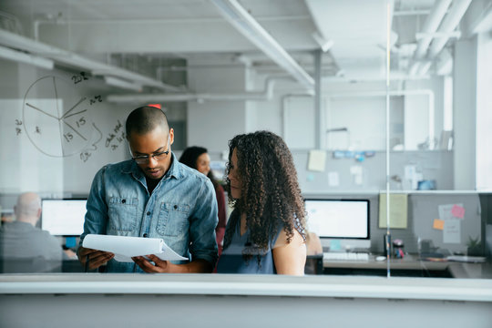 View through window of coworkers reading documents in office