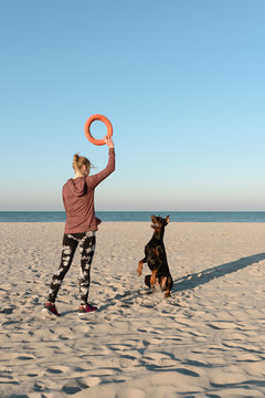 Woman training Doberman dog on beach