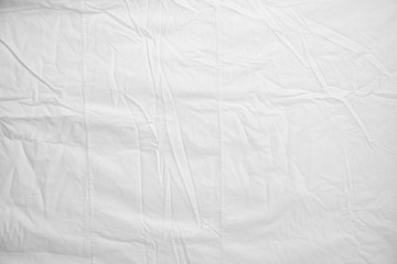 White Crumpled Bed Sheet Background Texture. white fabric top view. pleats on light fabric