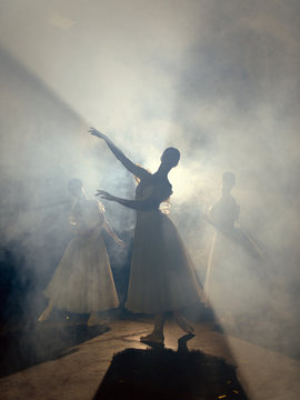 Ballerinas dancing on scene in darkness