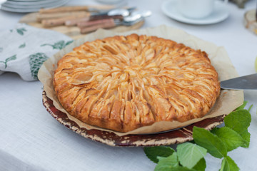 Homemade apple pie on the tablecloth decorated with green leaves