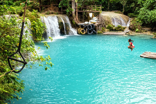 Woman jumping in a waterfall in The Philippines