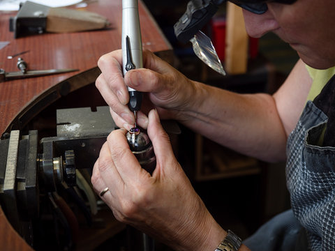 Woman making jewellery for clients working from a small workshop in her home.