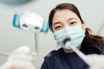 Personal perspective of female dentist with mask at work