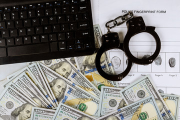 Cyber financial crime with handcuffs on money US hundred dollar bills to fingerprinting crime page file