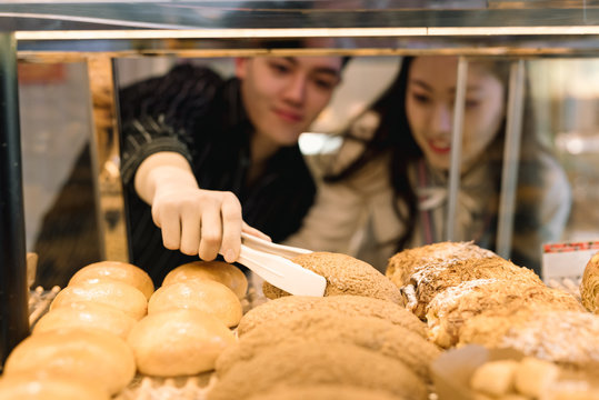 Young couple buying bakery products in store
