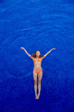 Overhead view of woman swimming underwater in a blue pool