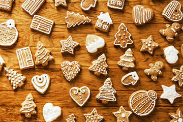 Ready Christmas gingerbread cookies in white sugar glaze lie on a wooden plane. Festive texture.