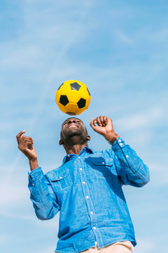 Fototapeta Black man playing with a yellow soccer ball outdoors