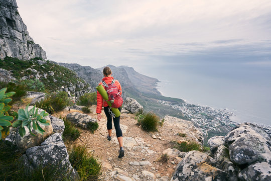 Female hiker on mountain track carrying a backpack and yoga mat