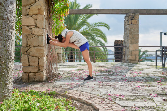 Athletic woman stretching on stone terrace