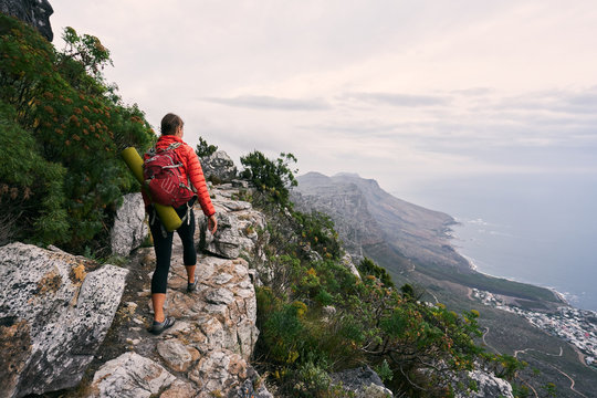 Female hiker on mountain track carrying a backpack and yoga mat