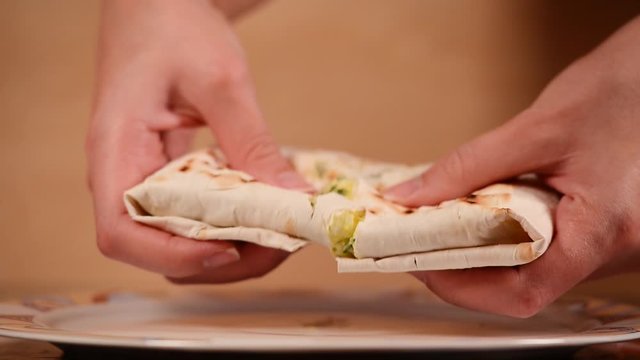 the girl picks up a homemade pie and breaks it into two halves. Melted cheese begins to stretch from one half to the other. Close up