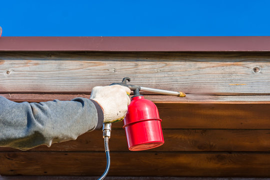 Initial treatment of wooden buildings with a protective coating using a spray gun