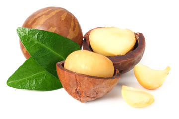 Macadamia nut with pieces and green leaves isolated on a white background