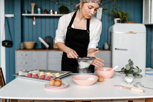 Woman sieving powdered sugar for macarons