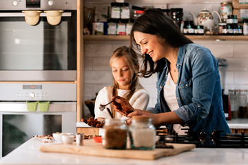Child with dough and cocoa near happy woman in kitchen