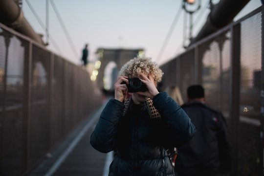 teen boy taking photos of NYC on Brooklyn bridge