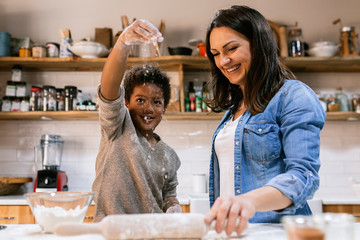 Black child and woman at table with rolling pin and different ingredients