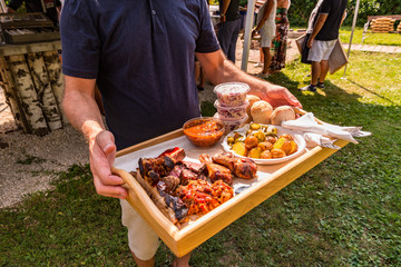 man holding bbq smoker food on wooden plate 